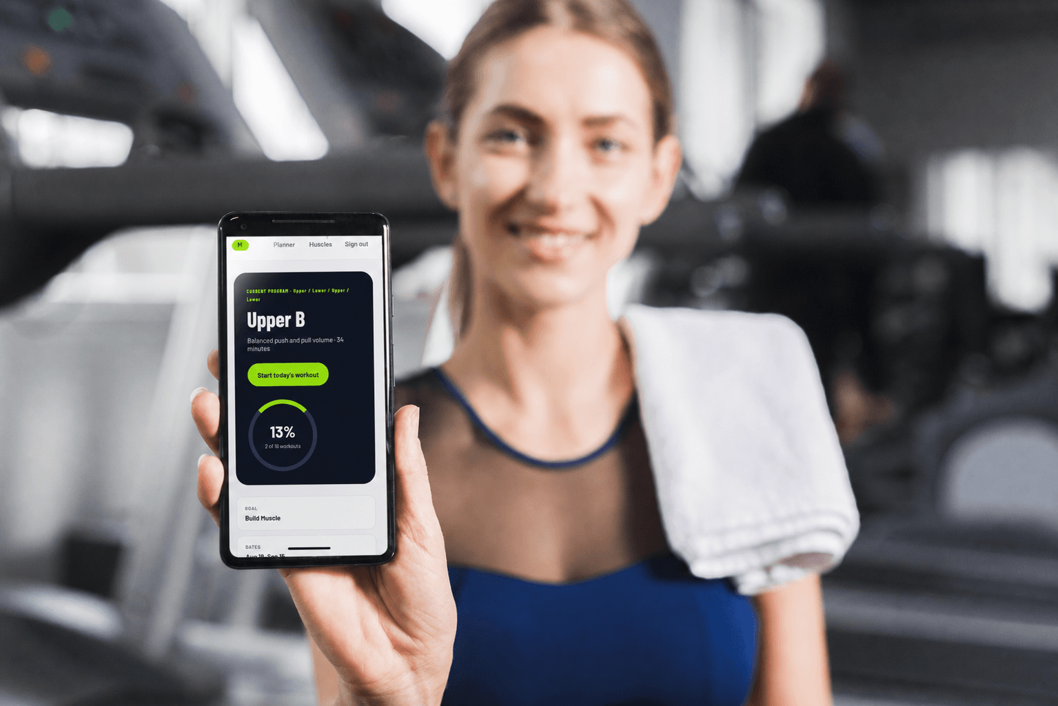 A member holding her phone with the Movenue workout dashboard open